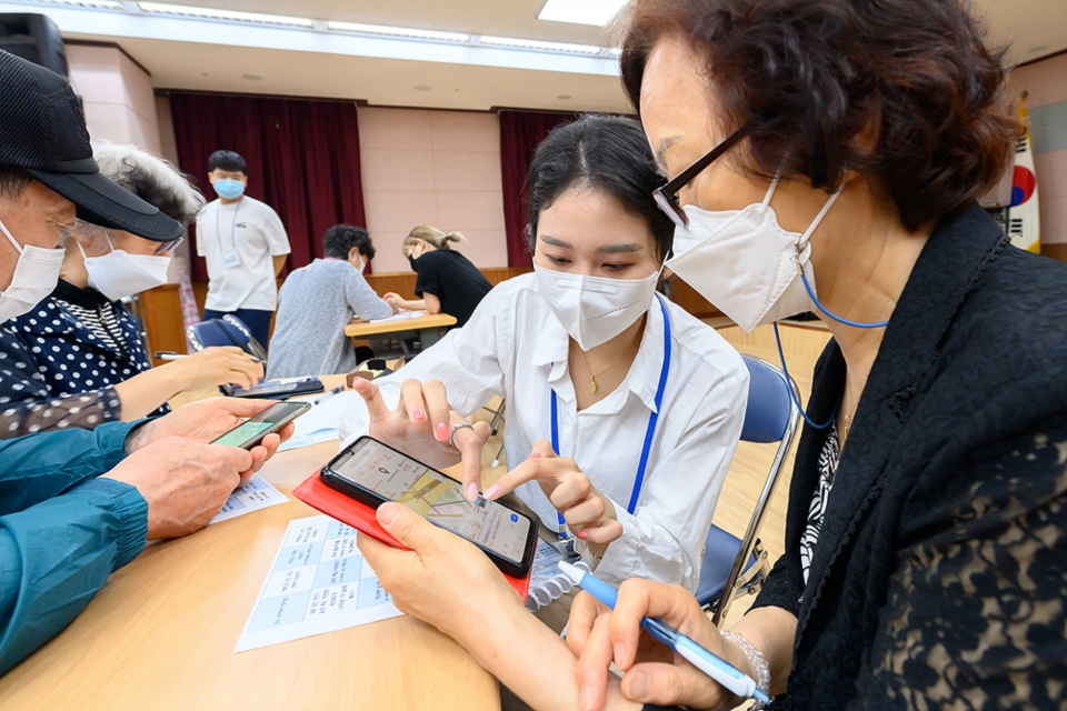 (지난달 서울 양천구 목3동 주민센터에서 청년들이 어르신들에게 스마트폰 활용 방법을 소개하고 있다. 사진=뉴시스 제공)