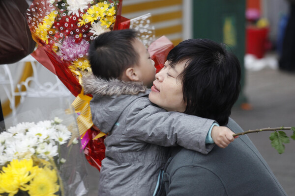 16일 북한 평양에서 한 여성이 어머니날을 맞아 꽃을 건넨 아들을 안아주고 있다. 사진=뉴시스 제공<br>
